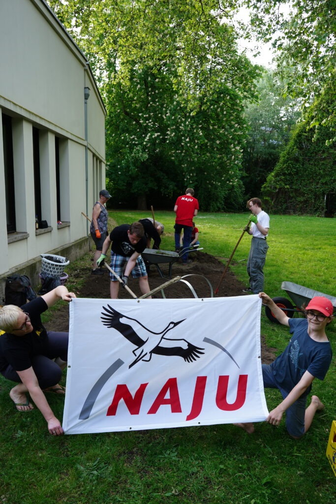 Bild von Grabung Blühwiese mit NAJU Flagge im Vordergrund